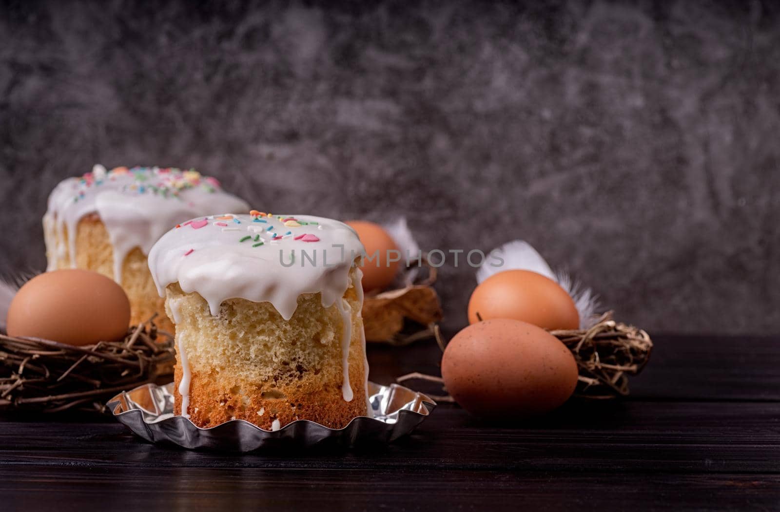 Easter holiday concept. Homemade Easter cake with white icing decorated with eggs on dark background with copy space