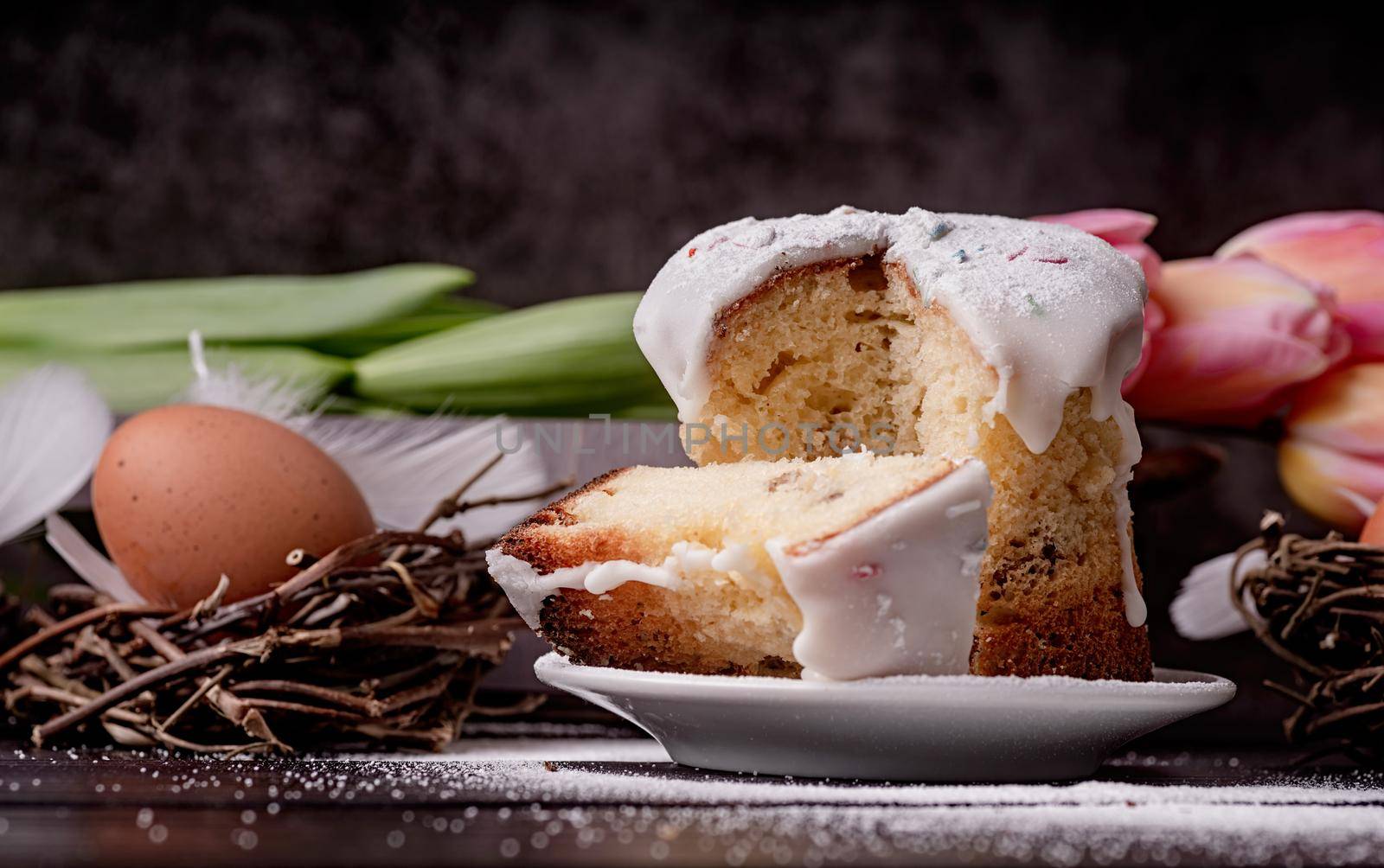 Easter concept. Baking and cooking. Glazed easter cake with tulips on dark rustic background