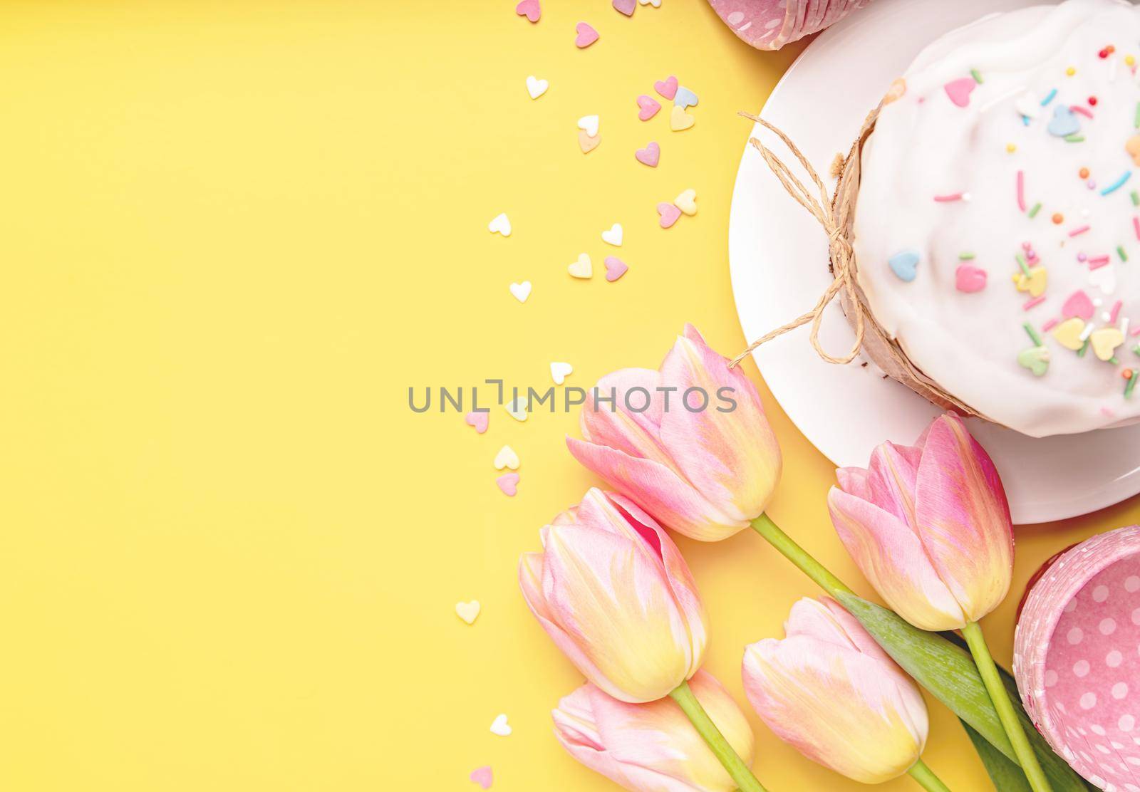 Easter cake with tulips, eggs and baking items top view on yellow background with copy space by Desperada