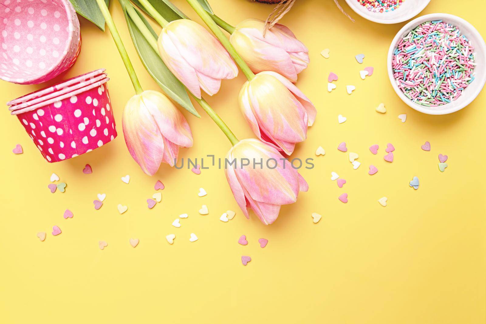 Easter cake with tulips, eggs and baking items top view on yellow background with copy space by Desperada