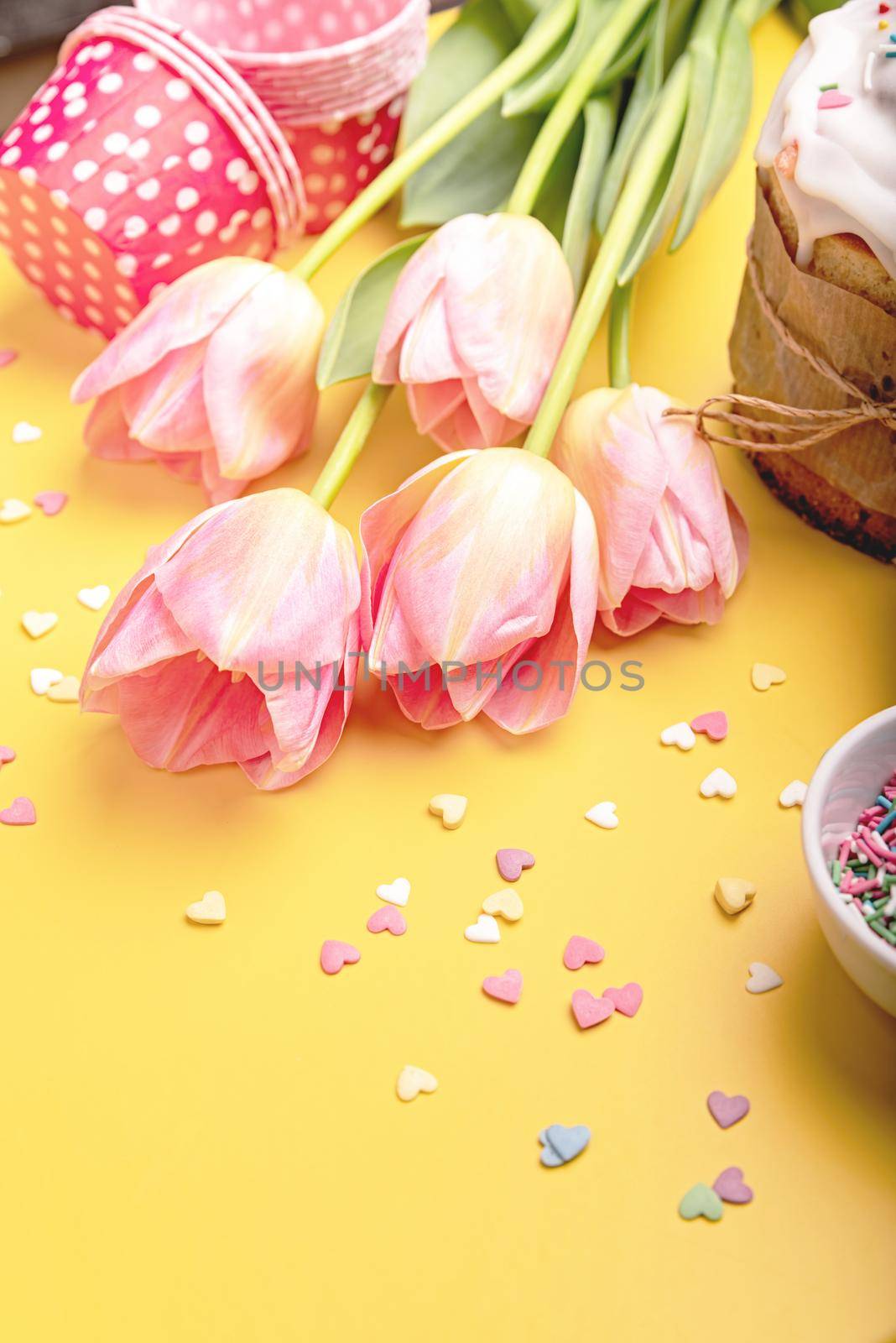 Easter cake with tulips and baking items on yellow background with copy space by Desperada