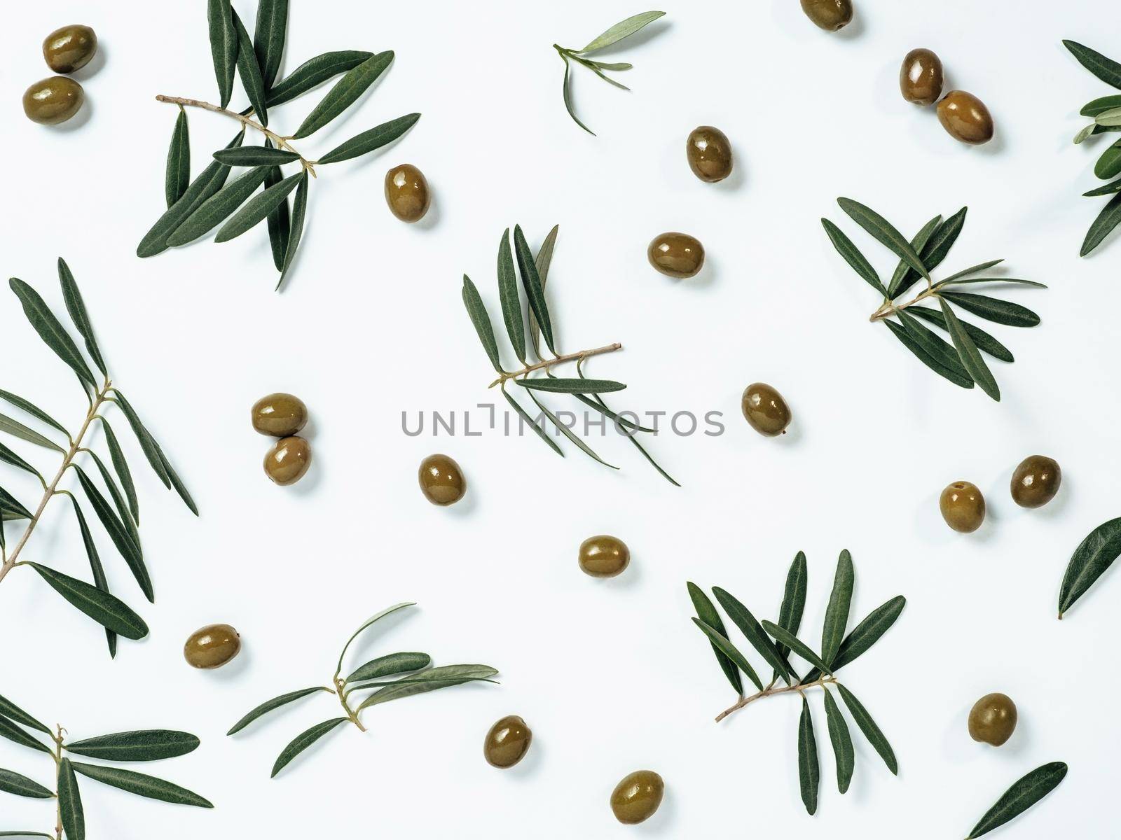 Beautiful pattern with green olives and olives tree leaves and branches on white background. Olive tree fruits and branches as pattern, top view or flat lay.