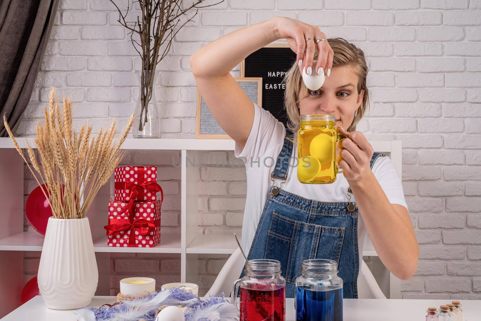 Easter concept. Woman coloring eggs at home. Young woman looking at the mason jar ready for coloring eggs front view