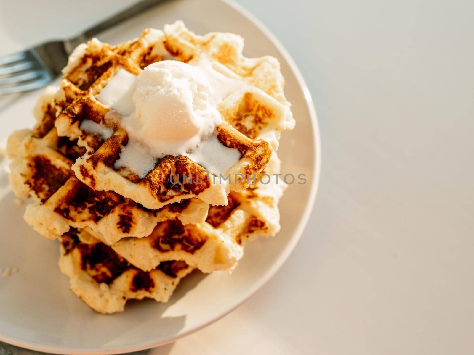 Ricotta cheese chaffles for keto diet. Stack of ricotta and lemon belgian waffles decorated with ice cream scoop.Copy space for text or design. Natural sunset or sunrise daylight. Top view or flat lay