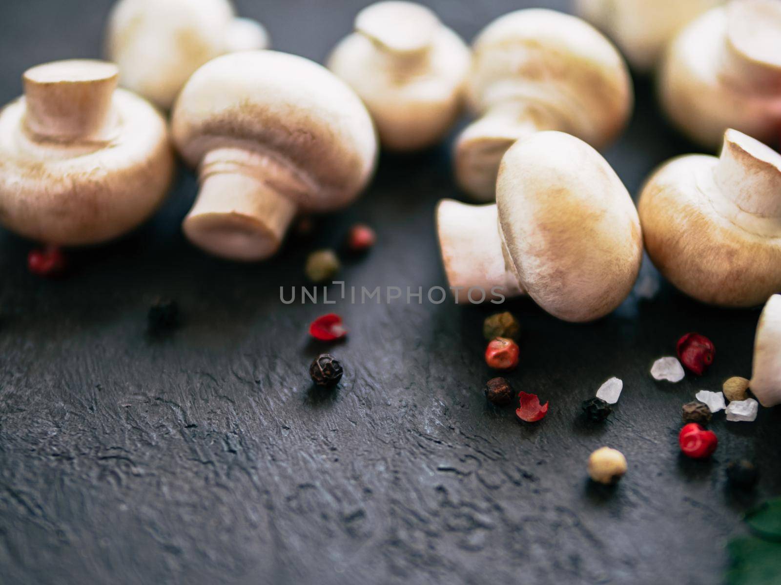 Mini champignons with copy space on left edge. Raw whole mushrooms on black background, copy space
