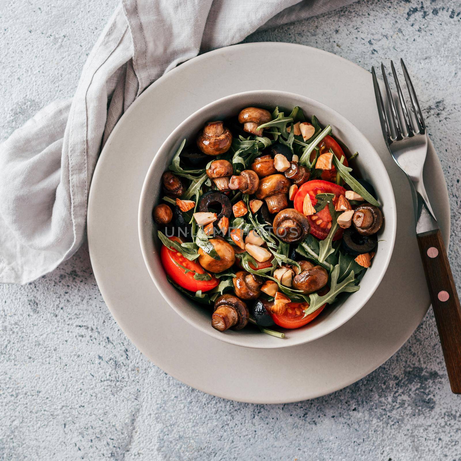 Salad with arugula, mini champignons, cherry tomatoes, black olives, pine nuts. Vegetarian salad top view or flat lay. Copy space. Horizontal