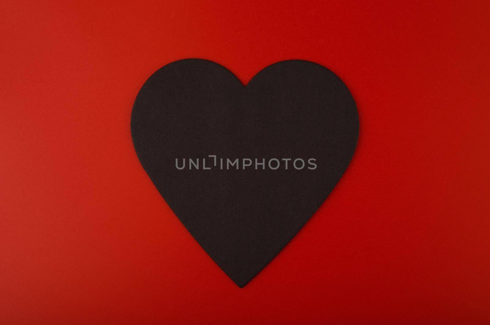 Close up of black paper heart against red background with copy space. Minimalistic concept of Valentine's day  by Senorina_Irina