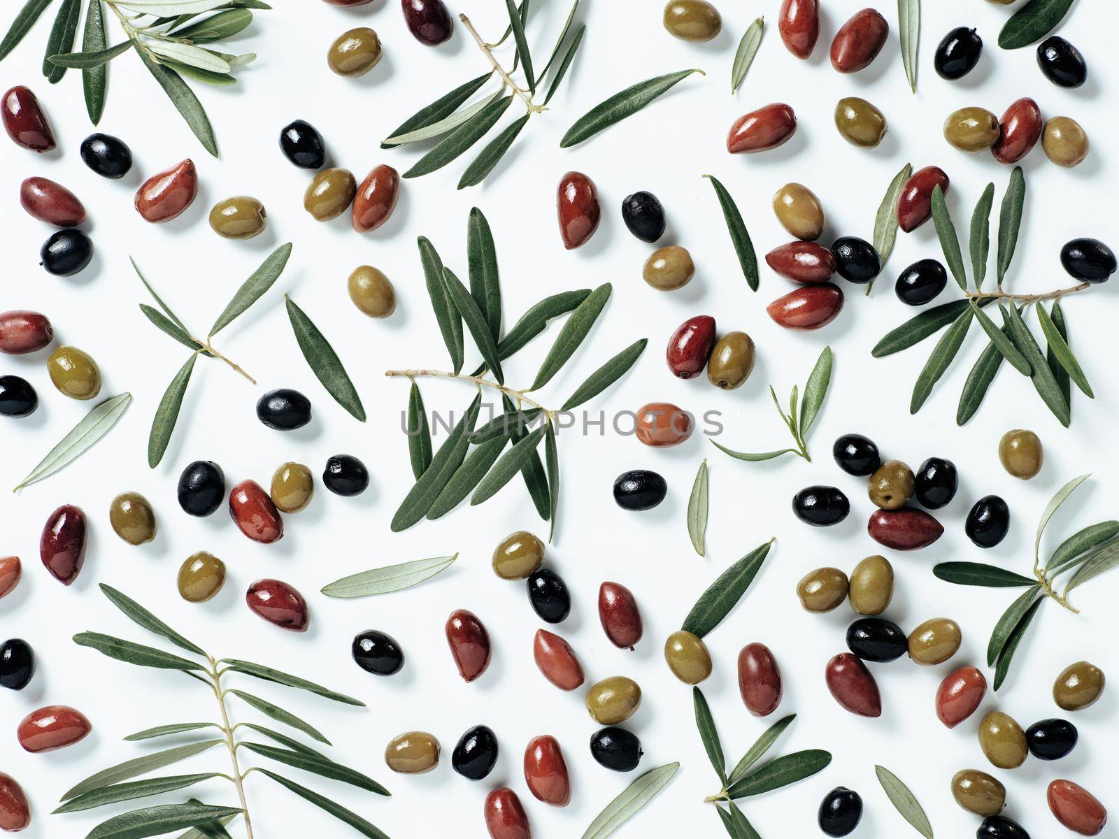 Beautiful pattern with green, black and red olives and olives tree leaves and branches on white background. Mix olive tree fruits and branches as pattern, top view or flat lay.