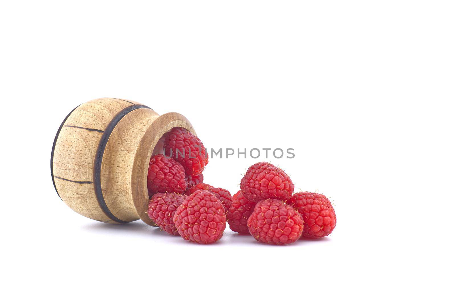 Fresh ripe raspberry spilled from a wooden pot isolated on white background
