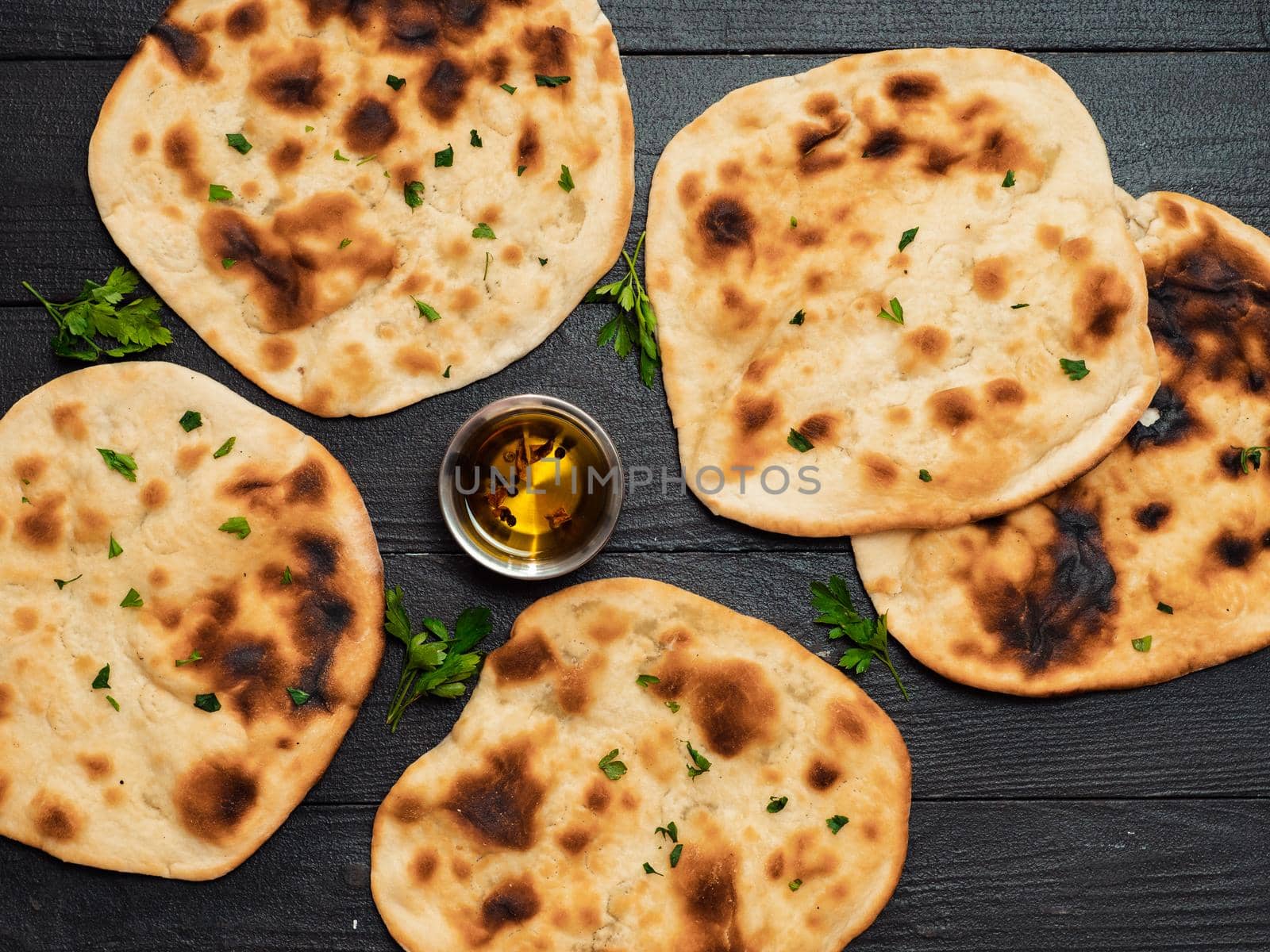 Fresh naan bread on dark wooden background with copy space. Several perfect naan flatbreads top view or flat lay.