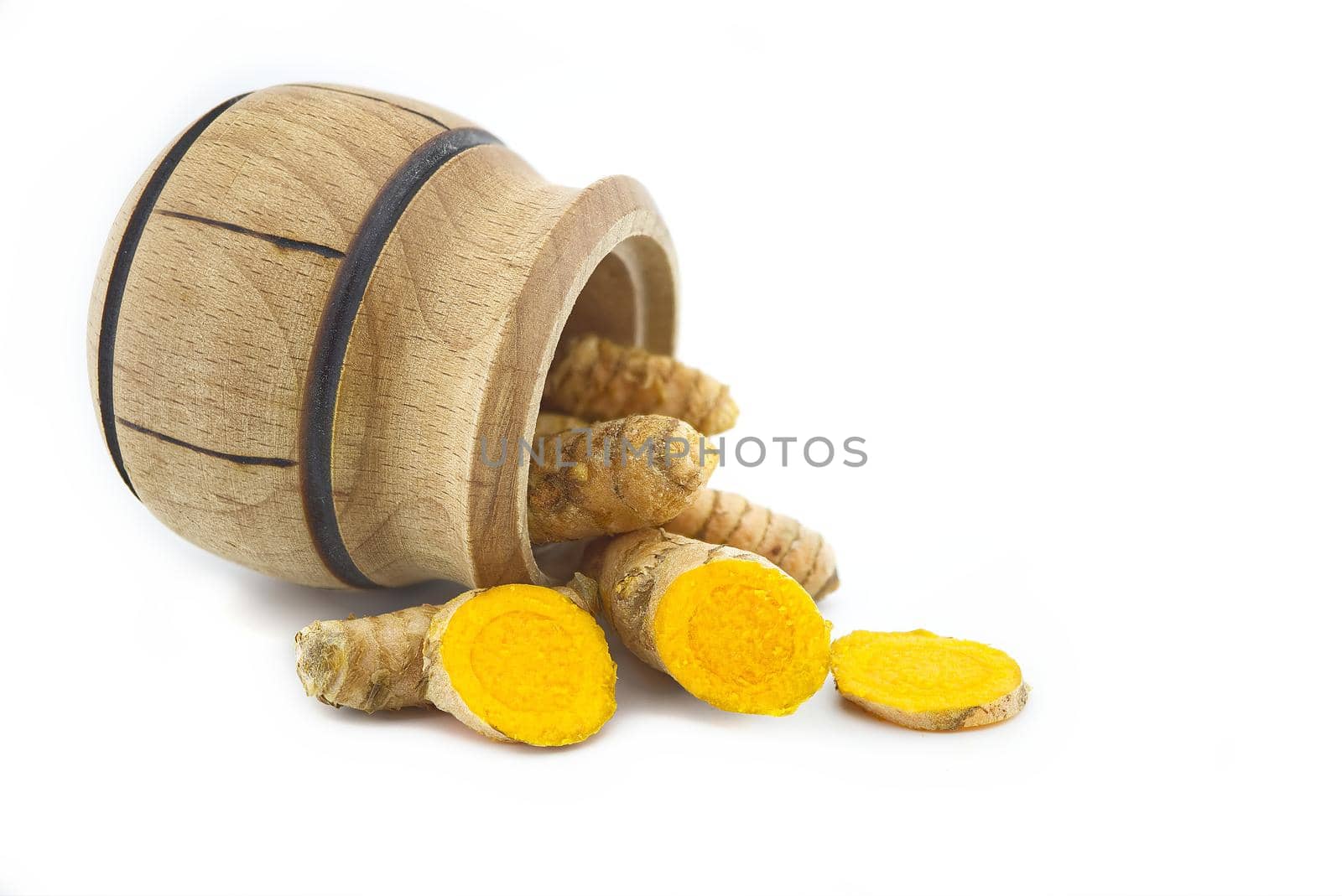 Turmeric roots and a small wooden pot isolated on white background
