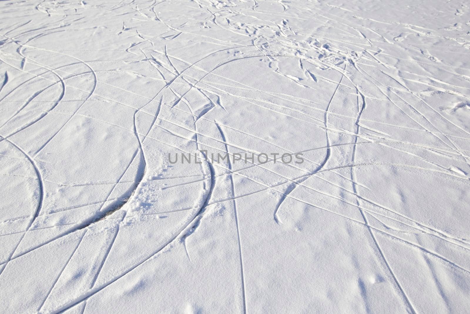 Skate tracks on ice with snowy snow. Winter background.