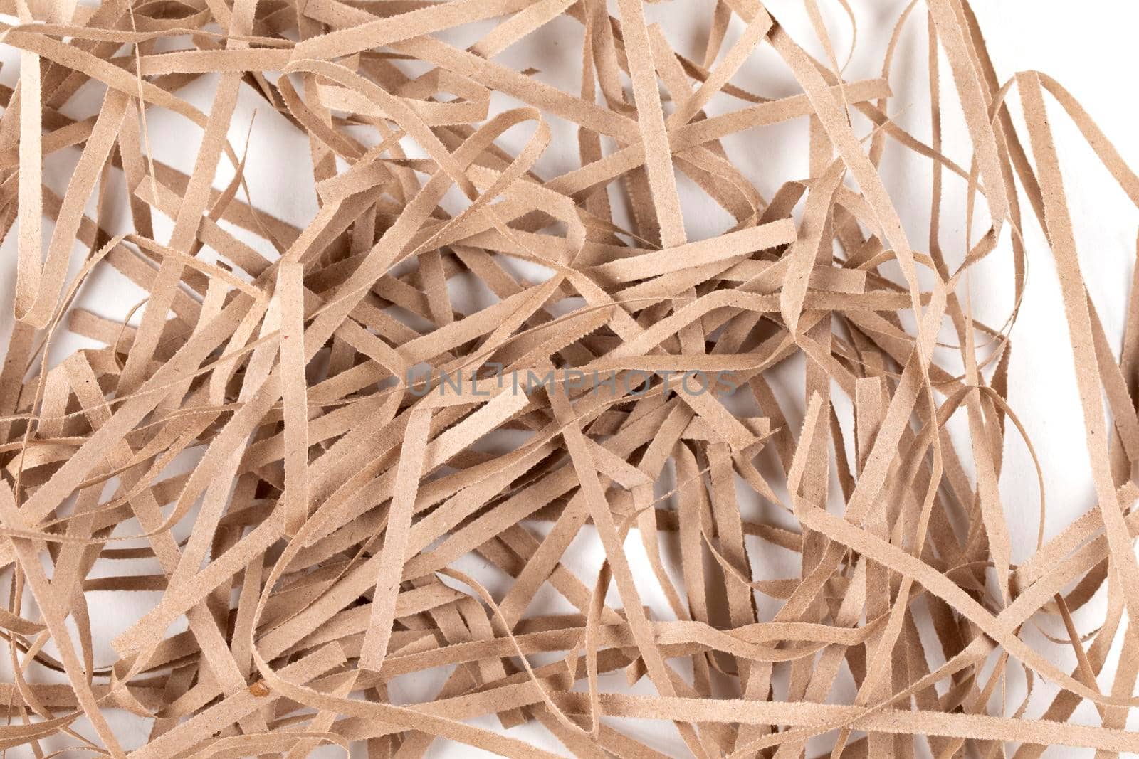 Lots of thin strips of beige paper. Decorative pieces of paper for gifts on a white background