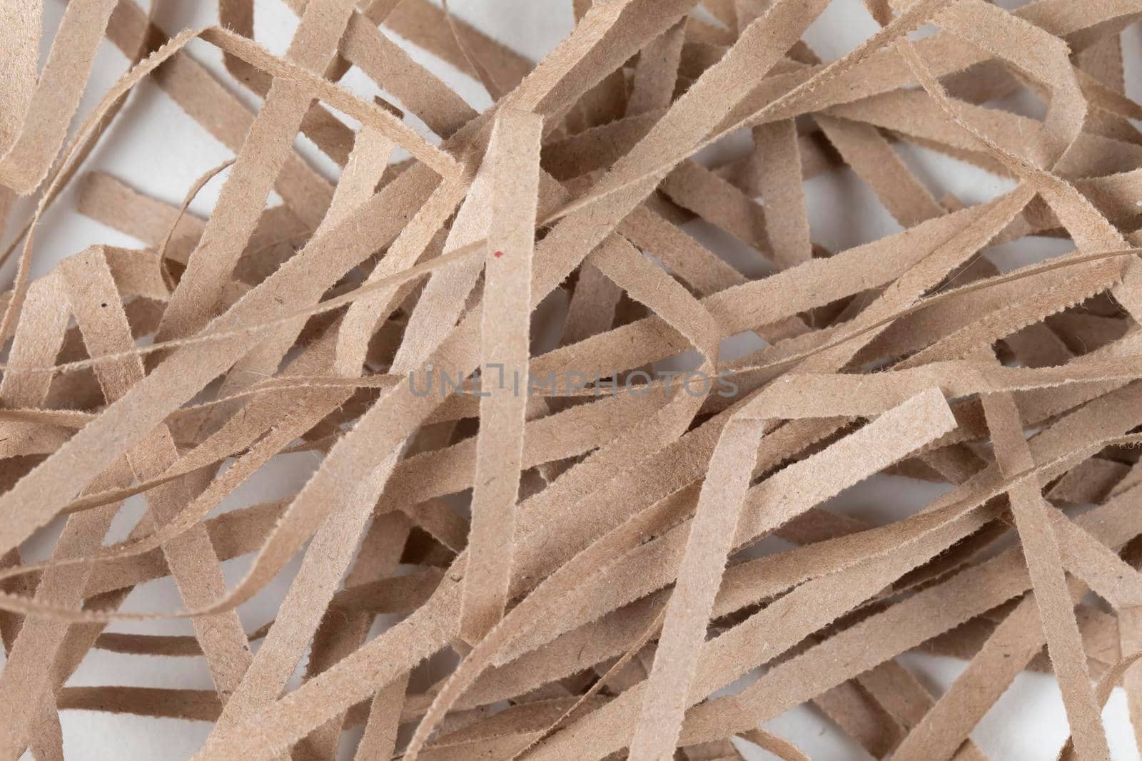 Lots of thin strips of beige paper. Decorative pieces of paper for gifts on a white background