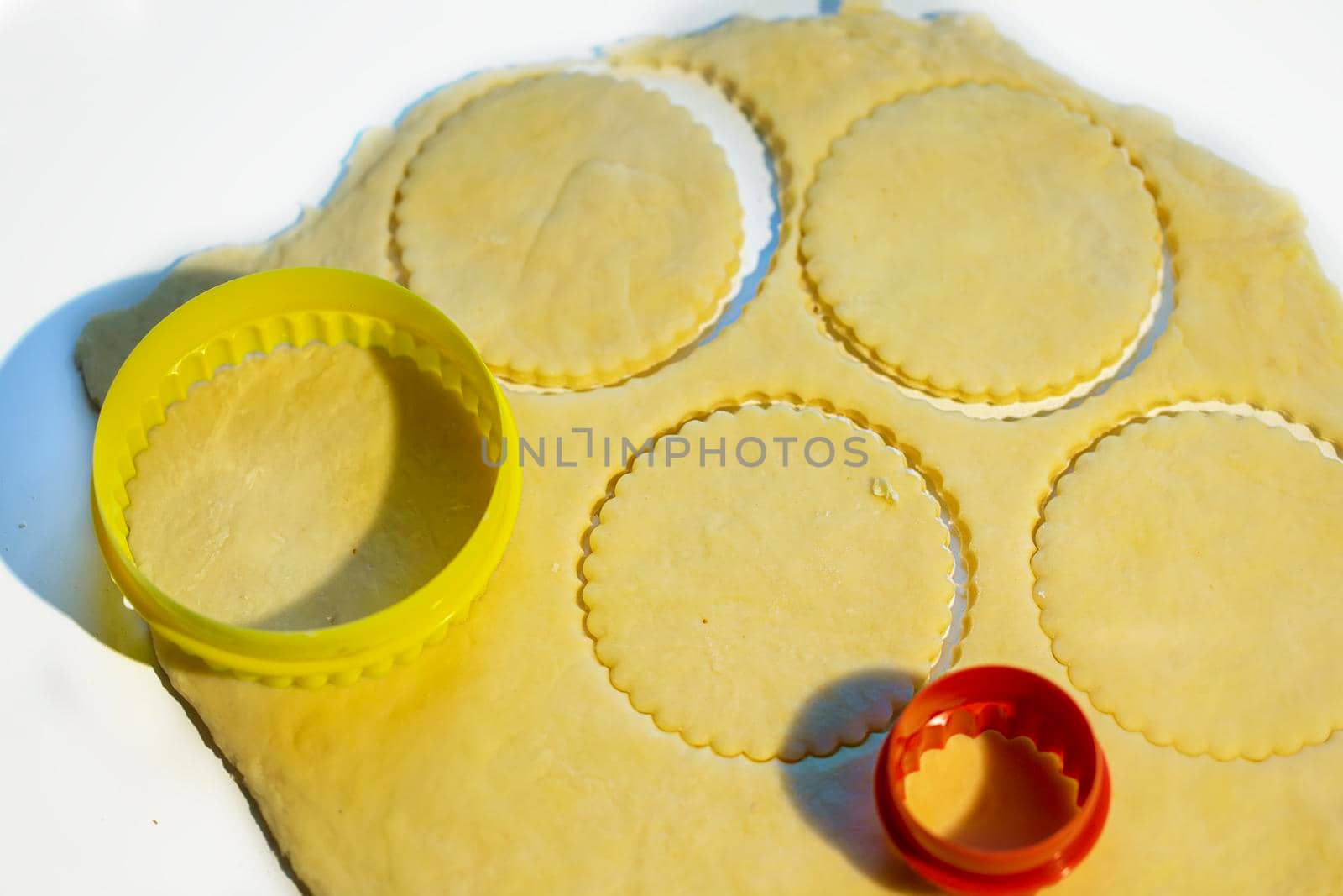 Dough rolled out on the table with multi-colored cookie cutters.