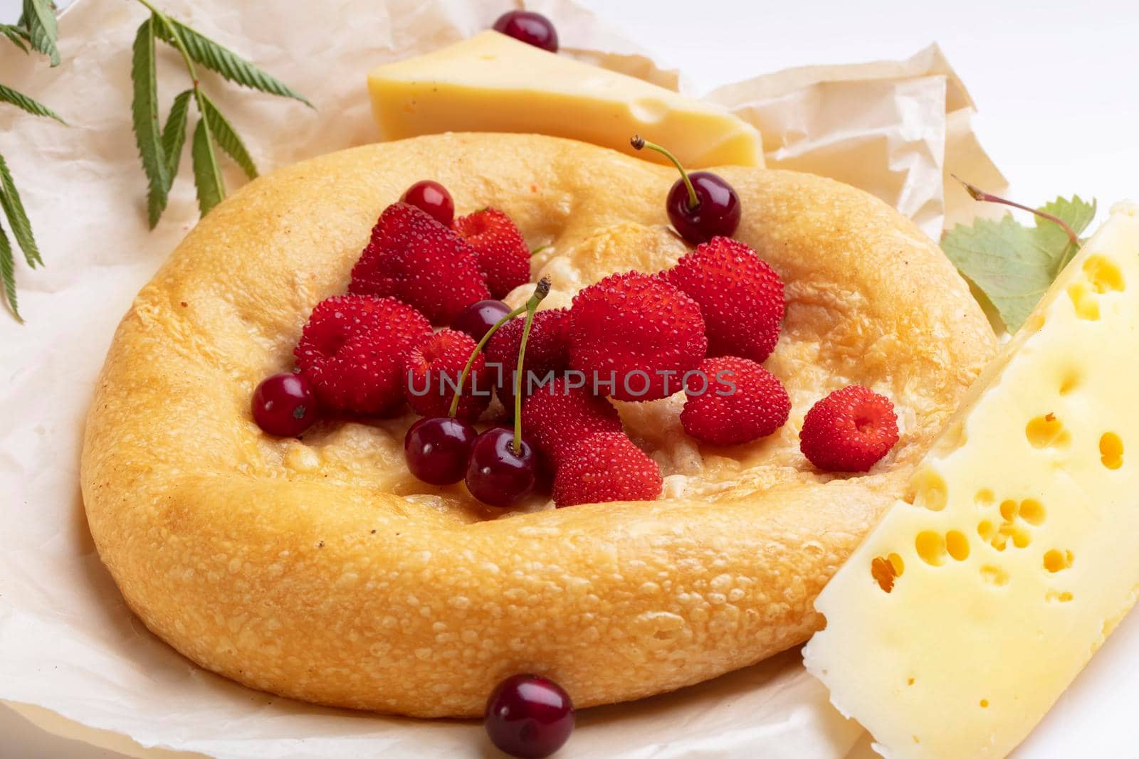 Lavash with red berries and a piece of cheese. Baked round bun for breakfast.