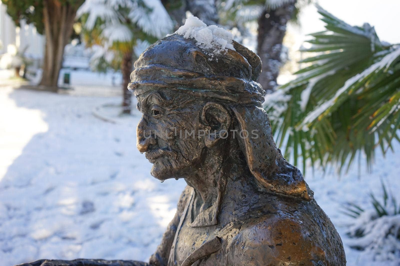 Sukhumi, Abkhazia-January 27, 2017: Urban landscape with sculpture on the background of snow and palm trees.