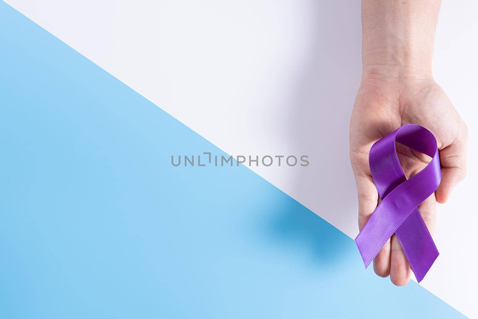 World cancer day, hands holding purple ribbon on with and blue background with copy space for text. Healthcare and medical concept. by mikesaran