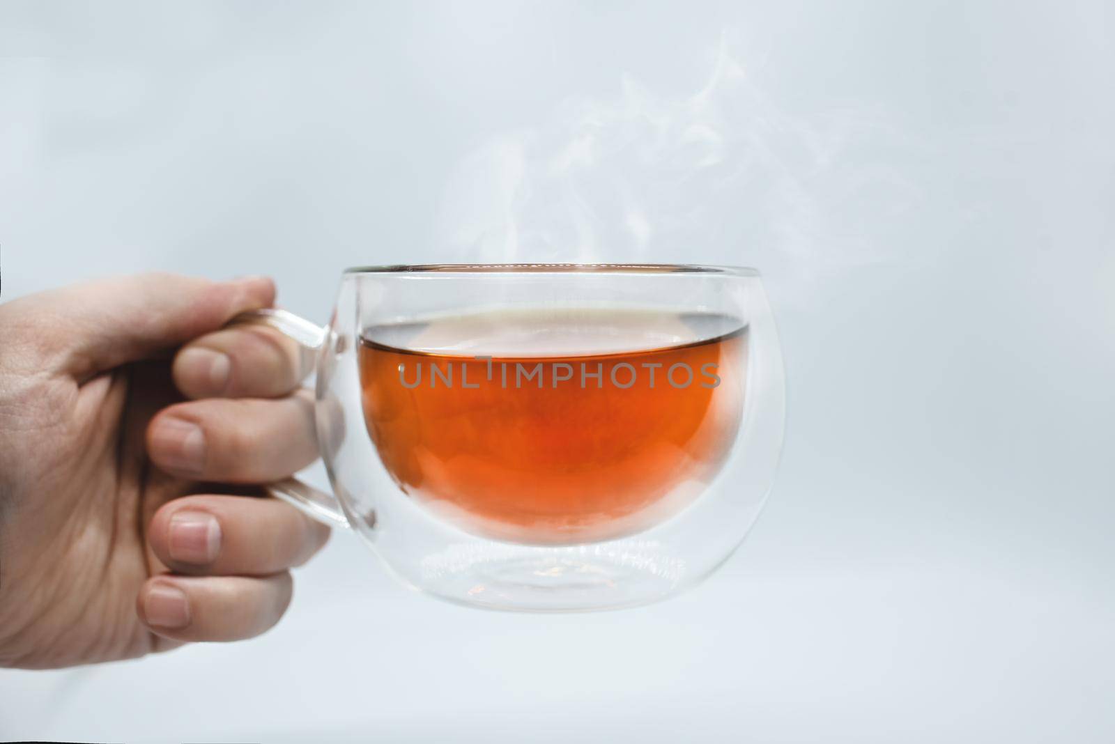 Man's hand holding a transparent cup with tea. Isolated on white background. Alpha
