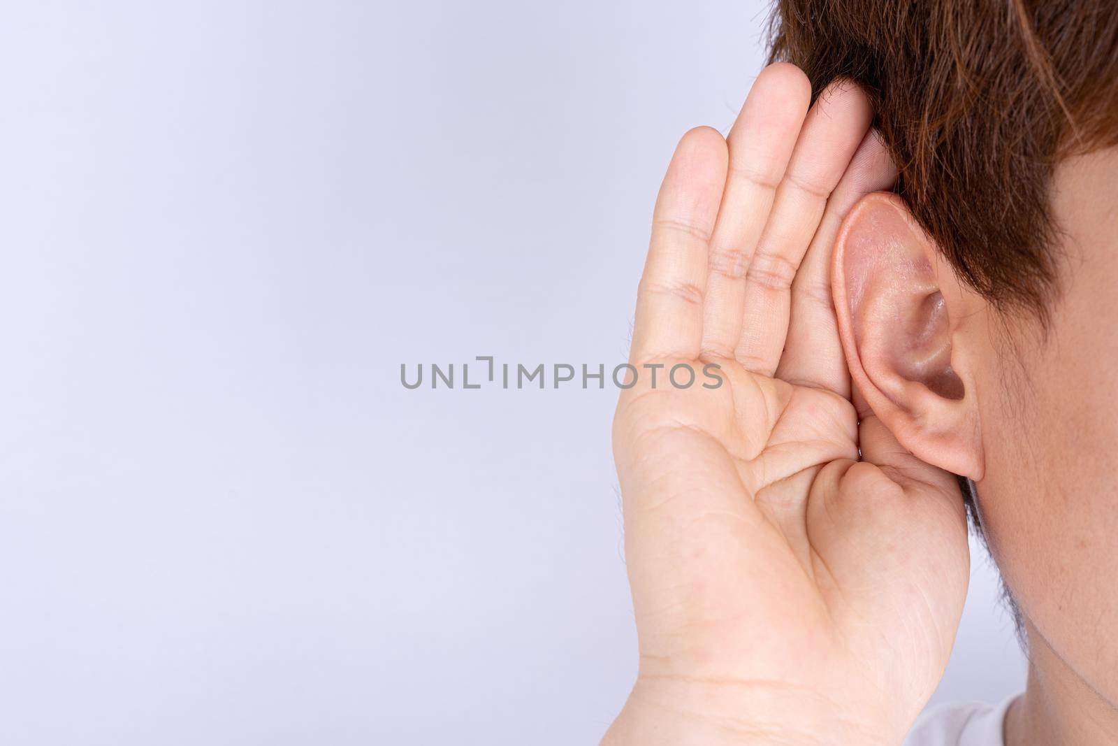 man hearing loss or hard of hearing and cupping his hand behind his ear isolate grey background, Deaf concept. by mikesaran