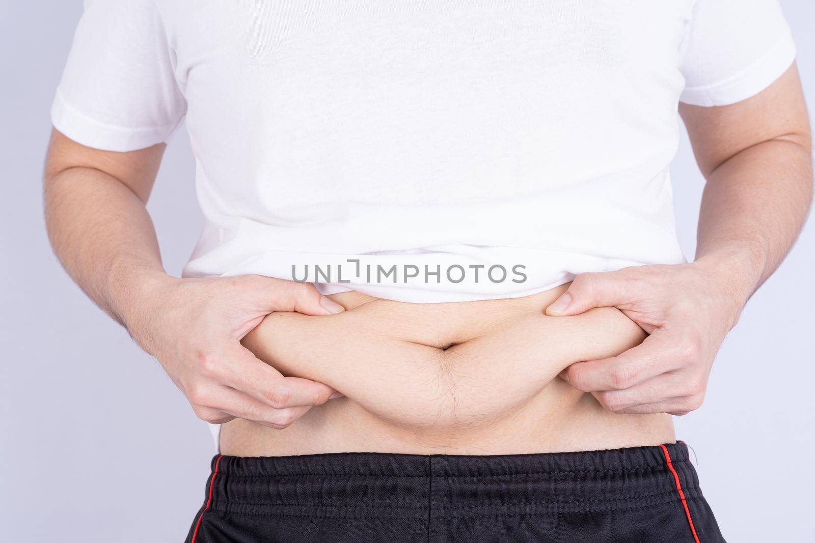 Fat man holding excessive fat belly, overweight fatty belly isolated grey background. Diet lifestyle, weight loss, stomach muscle, healthy concept. by mikesaran