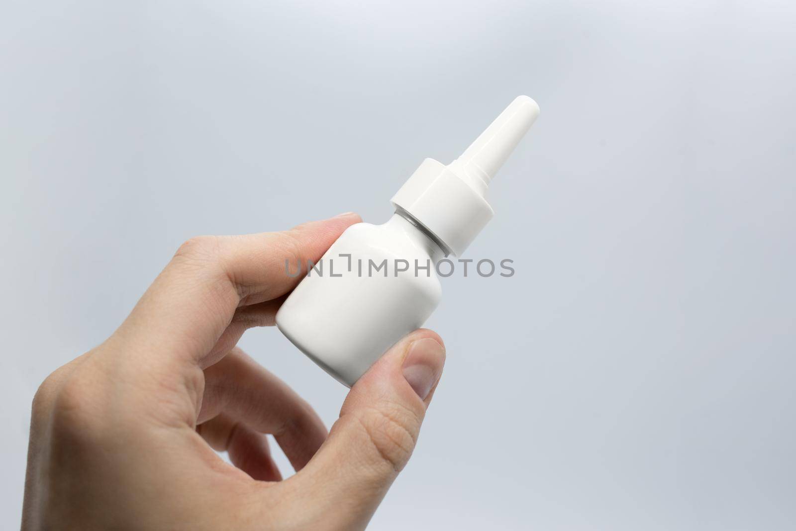 Young man is sick using nasal spray for blocked nose, spraying nose drops, hand holding nasal spray,