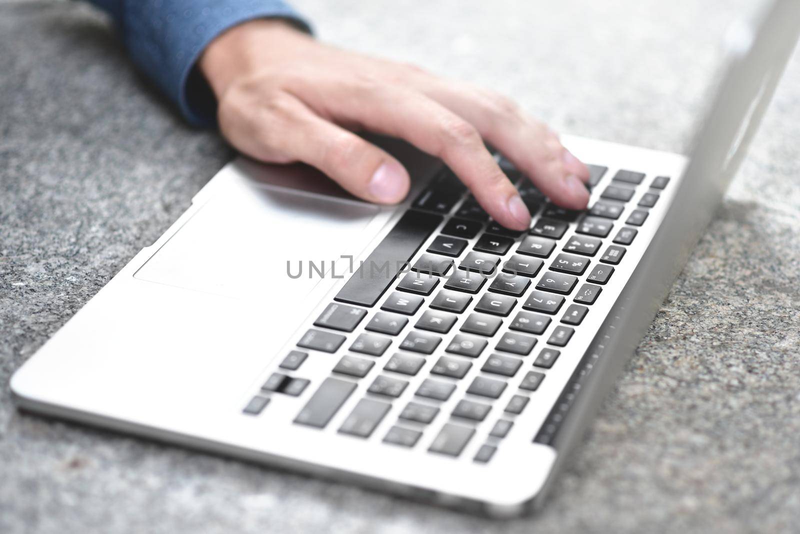 businessman sitting at street working with laptop, close-up photo. Business, education, lifestyle concept. by Nickstock