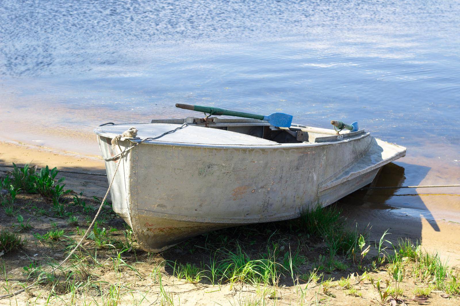 Old small fishing boat with paddles standing on river bank