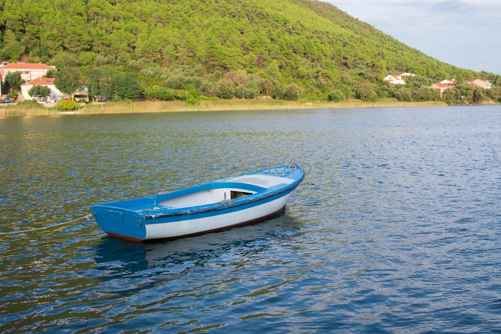 Small fishing boat in Mediterranean sea bay of Adriatic Croatia tied to shore