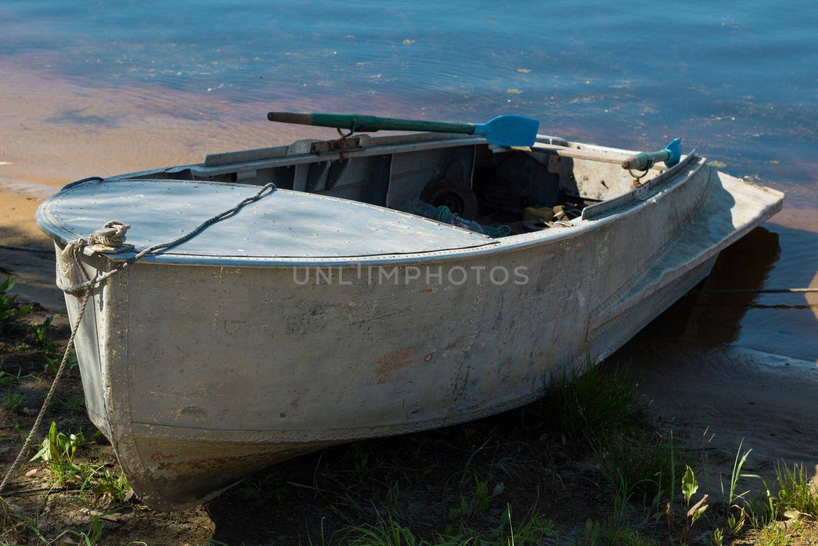 Small fishing boat with paddles standing on river bank by VeraVerano