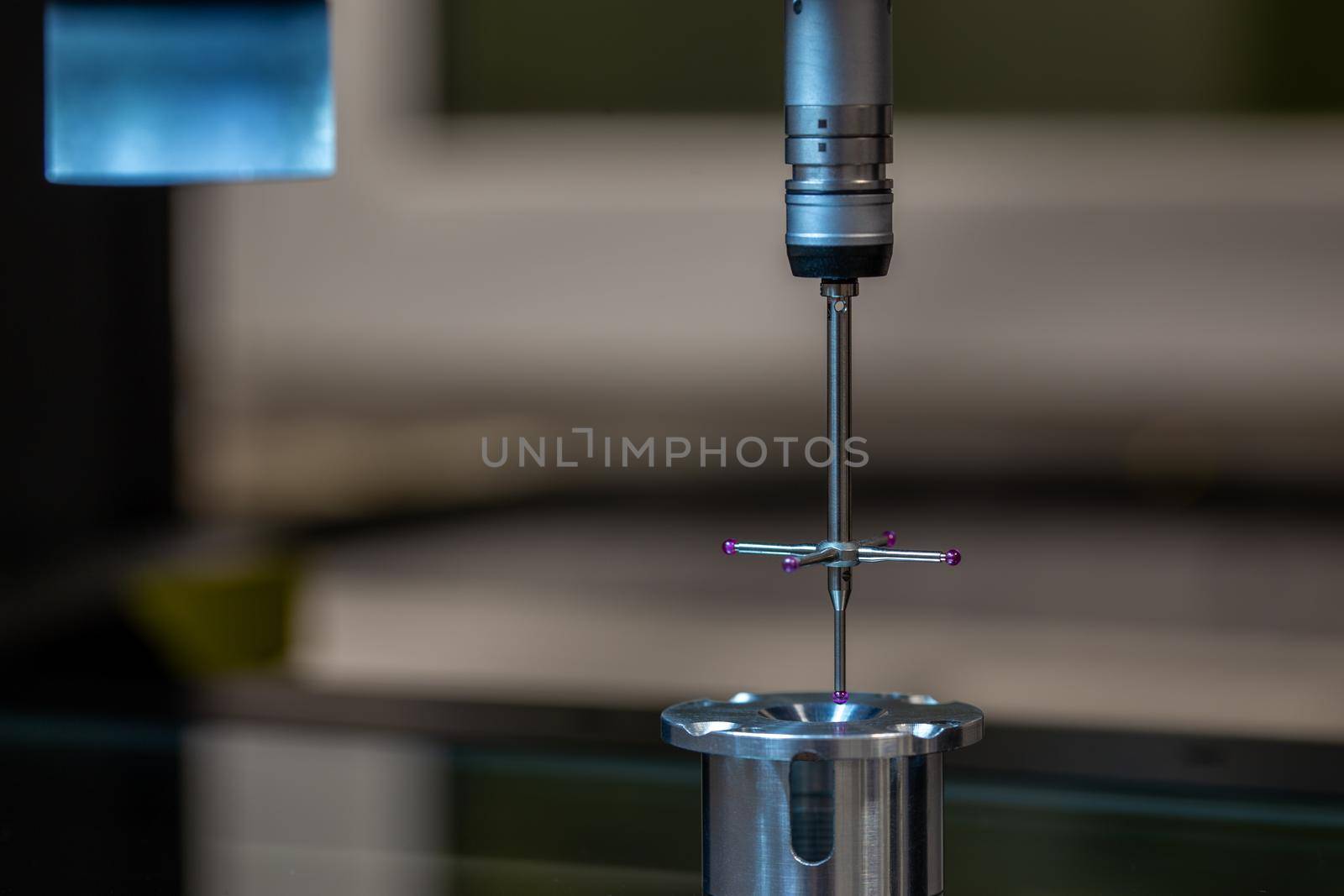 CMM - Coordinate Measuring Machine - contact probe measure aluminium sample part on glass table surface. High precision production metrological control process. Close-up macro shot with background blur.