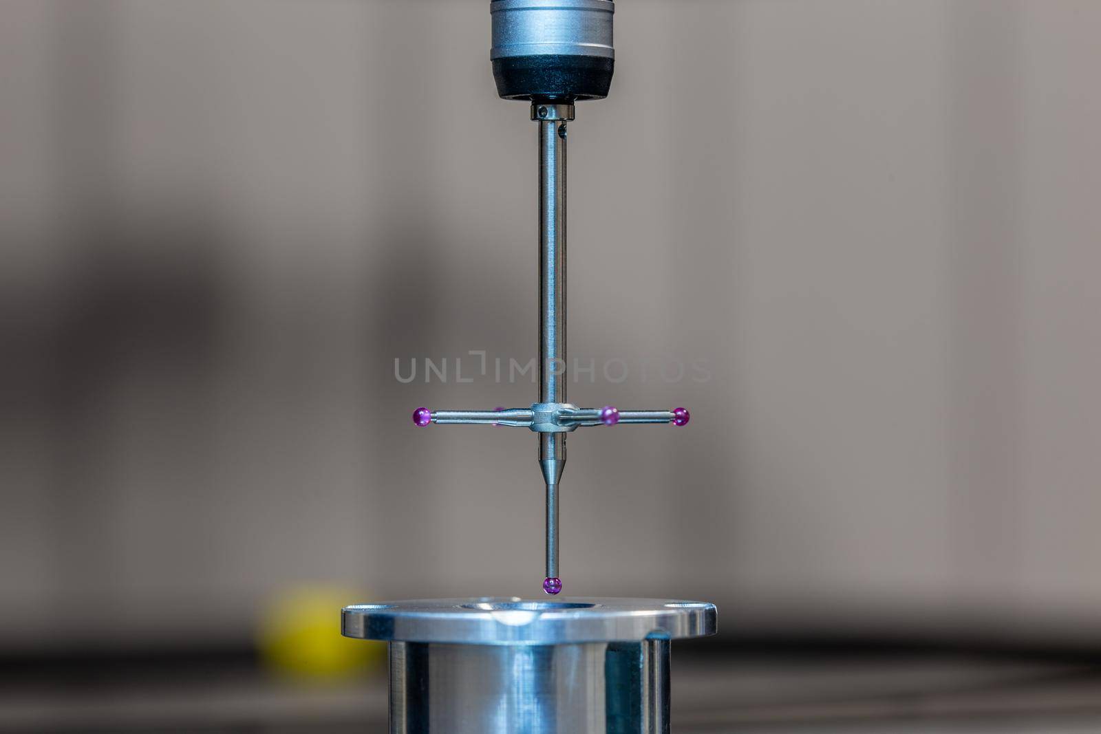 CMM - Coordinate Measuring Machine - contact probe measure aluminium sample part on glass table surface. High precision production metrological control process. Close-up with background blur.