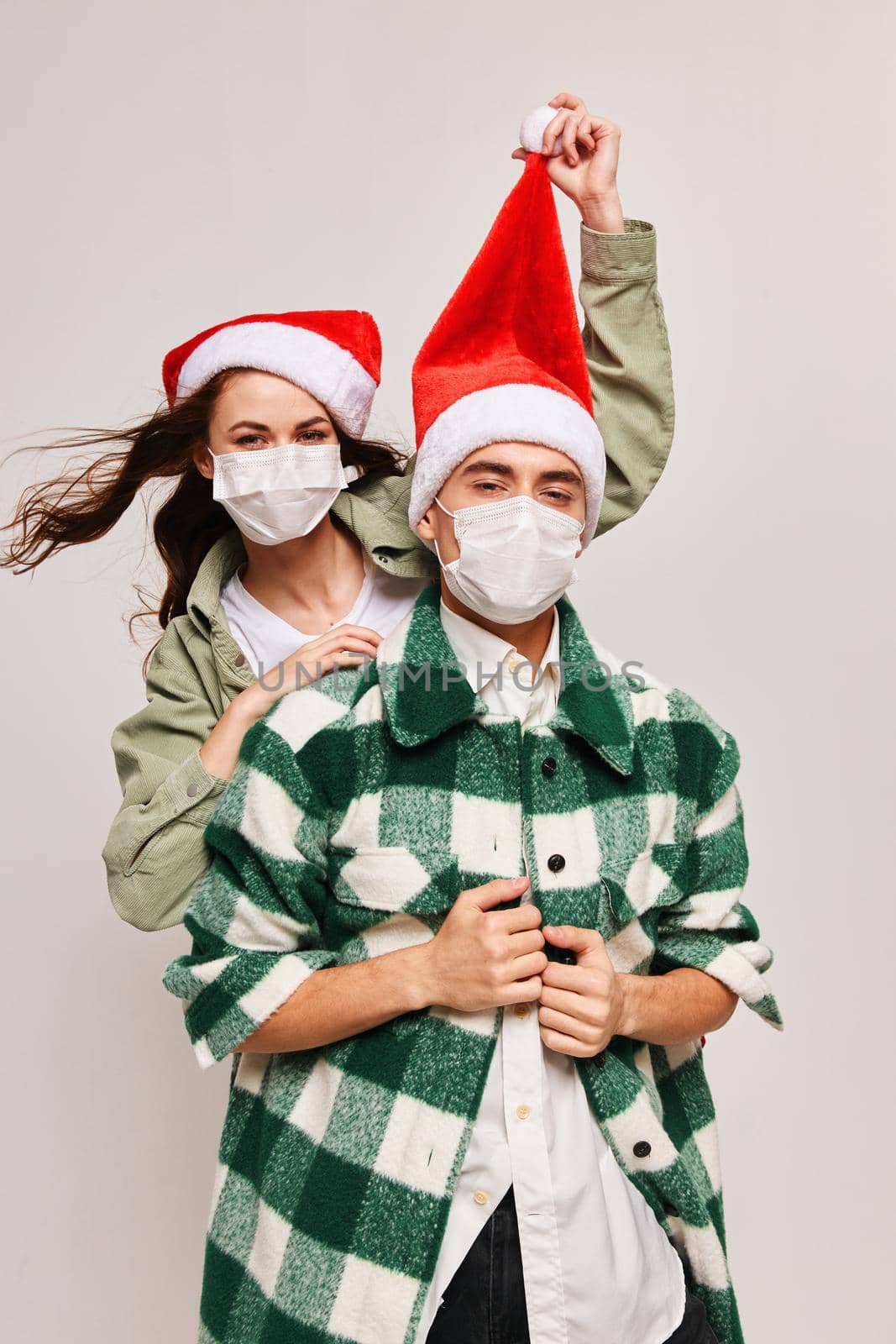 A man in a plaid shirt and a happy woman in a medical mask with a festive hat on her head by SHOTPRIME