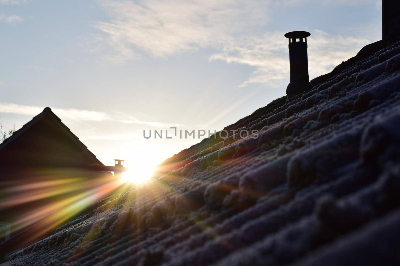 Sunrise over a frozen roof with moss against a blue sky with few clouds