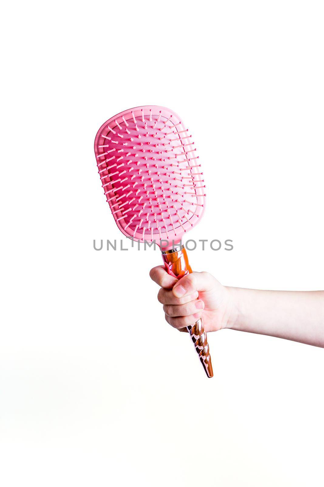 Beautiful pink comb brush in the hand of a girl on a white background