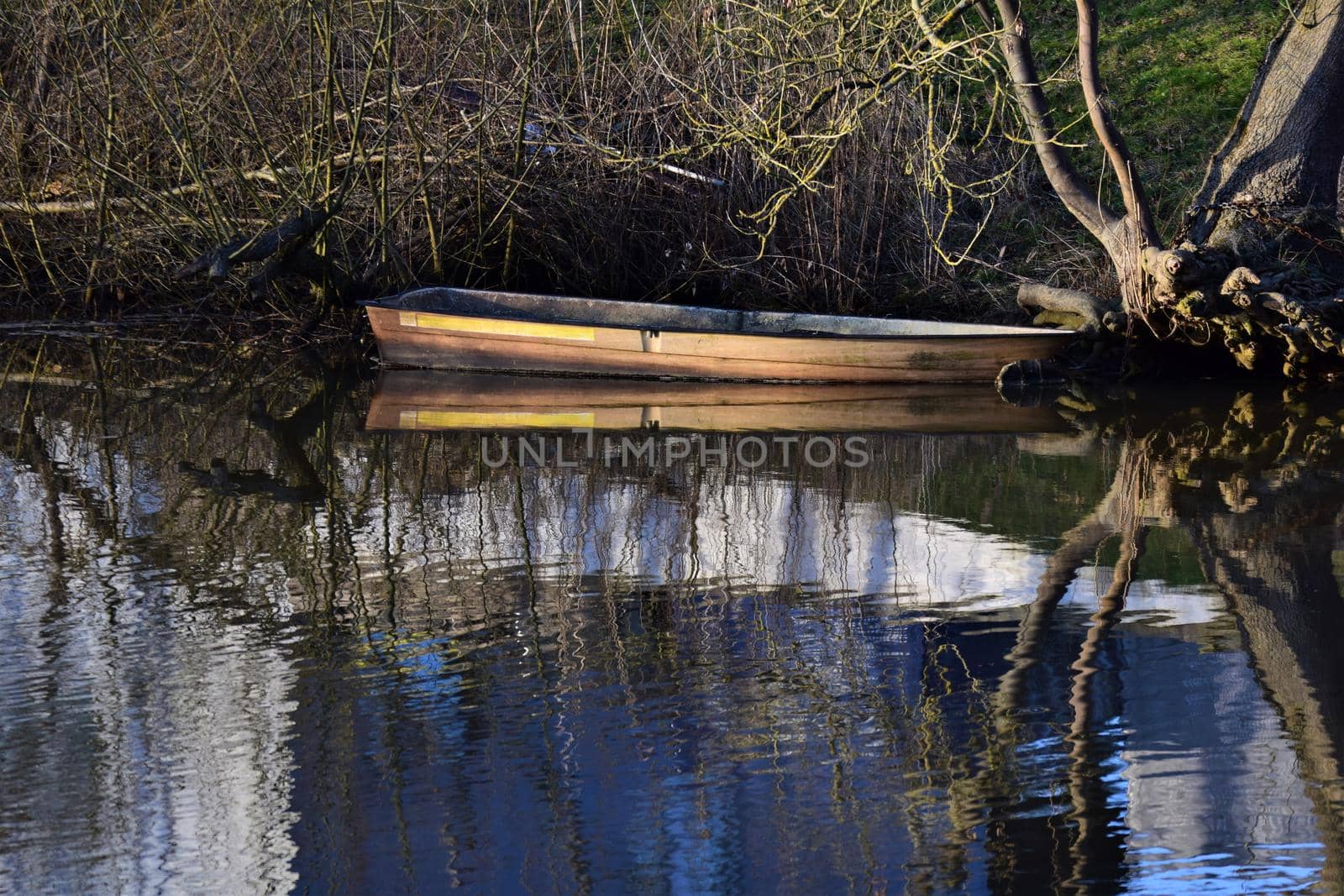 Old row boat on the bank of a river refleceted in the water