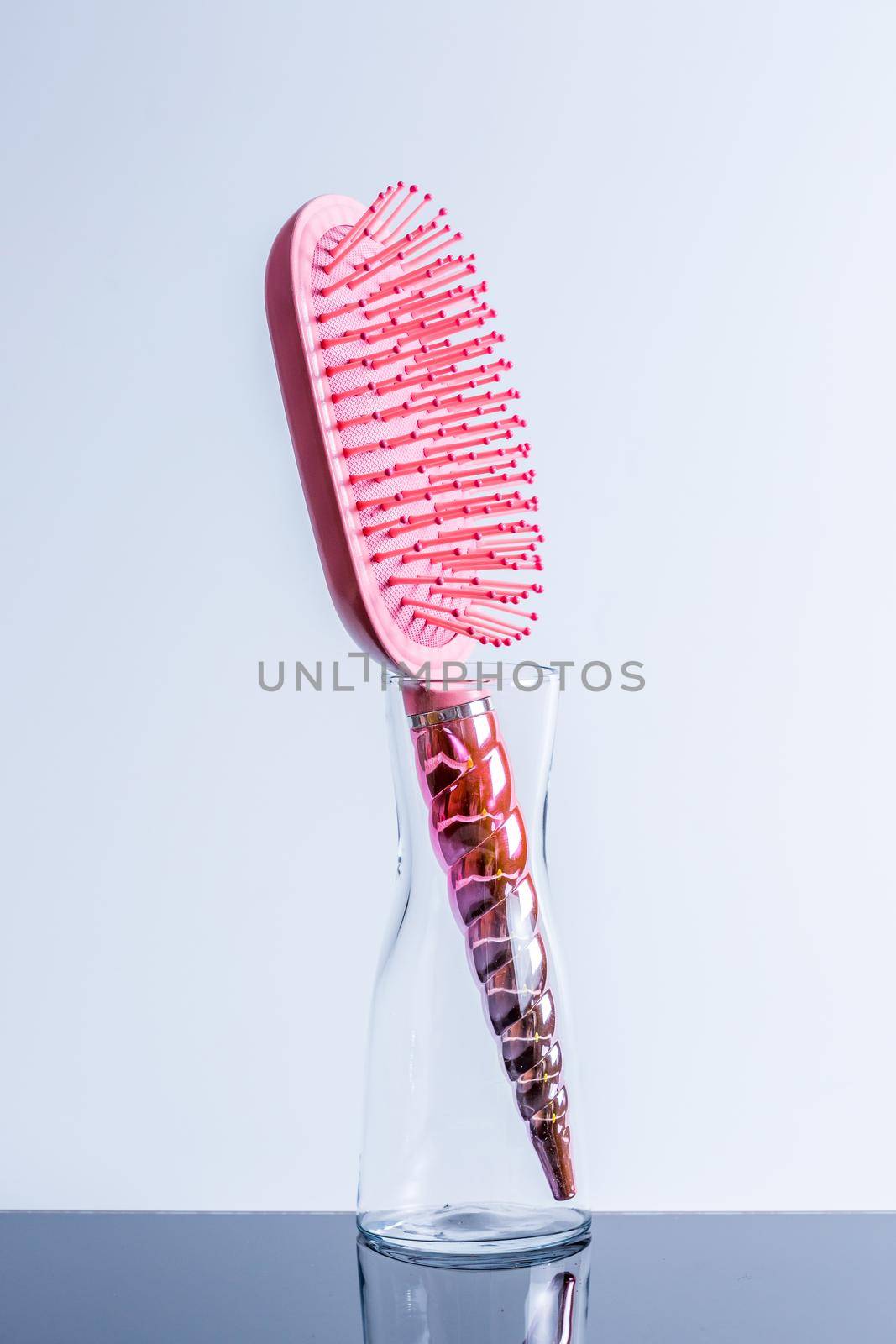 Beautiful pink comb brush in a transparent vase on a black glossy table by galinasharapova