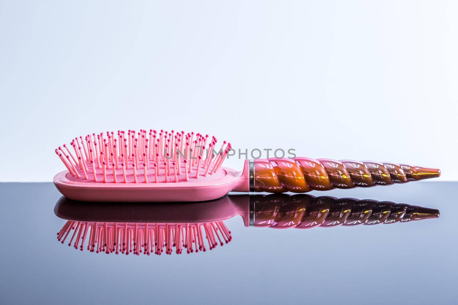Beautiful pink hairbrush on a black glossy surface. Women's Hair Care Accessories. Side view