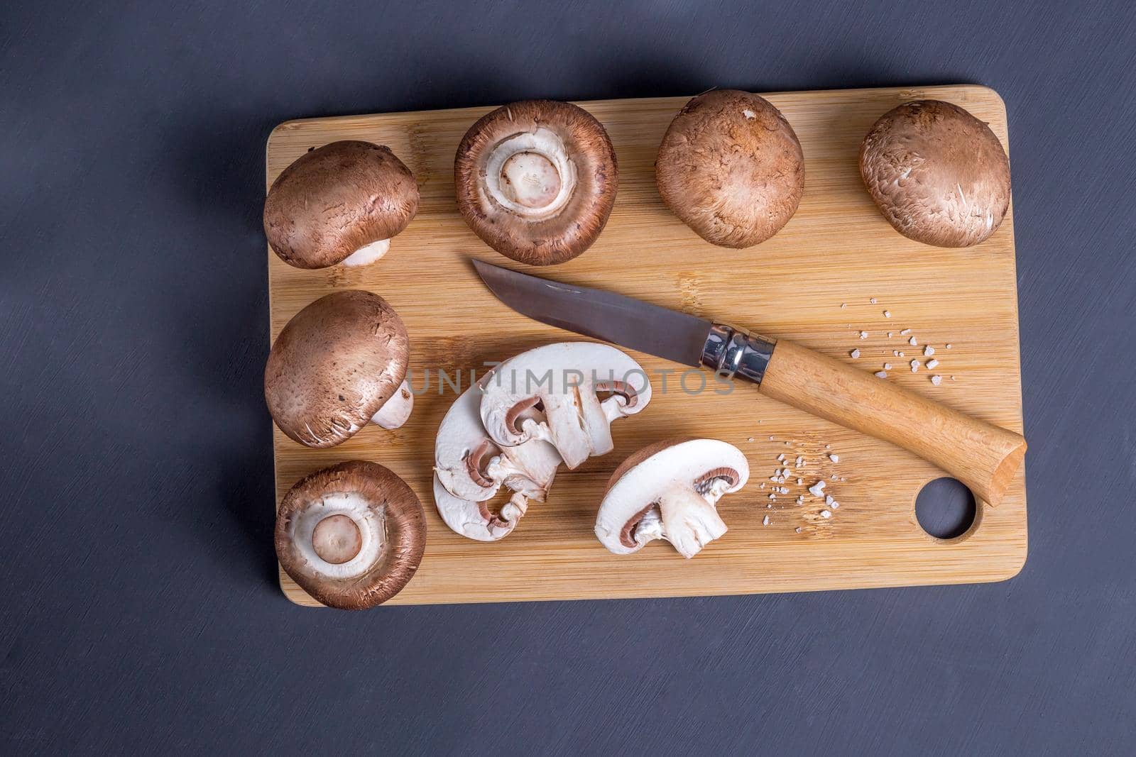 Royal champignons, Parisian champignons, mushrooms on bamboo wooden chopping board. Dark wooden background. Top view.