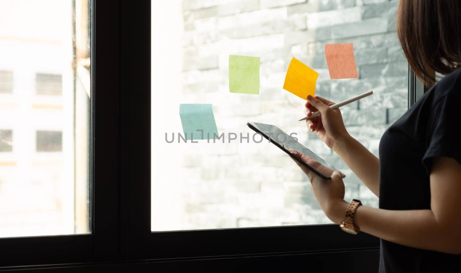 business woman using tablet during post it notes idea discussing and planning in glass wall at meeting room, business concept. by nateemee