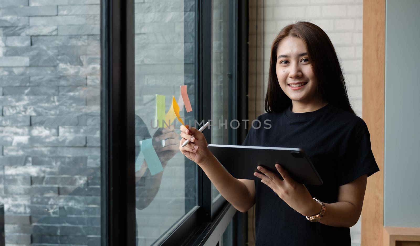 Portrait business woman using tablet during post it notes idea discussing and planning in glass wall at meeting room, business concept