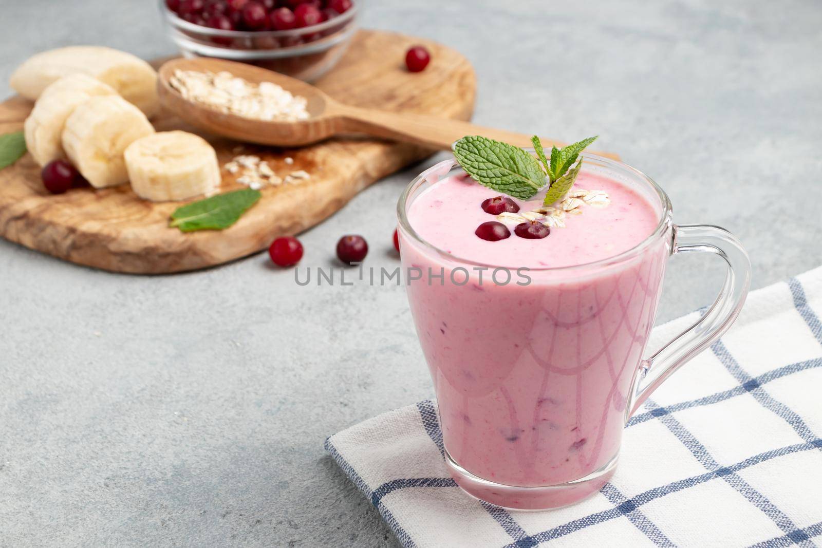 Homemade yogurt smoothie with banana, cranberry and oatmeal, copy space.