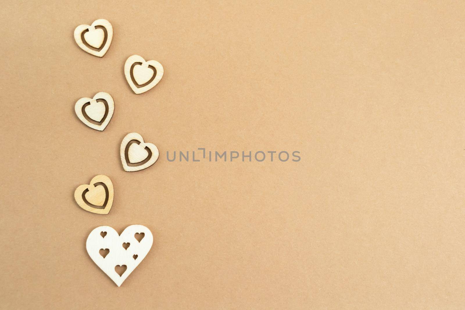 Wooden hearts on a pastel craft paper background. Abstract background with wood cut shapes. Sainte Valentine, mother's day, birthday greeting cards, invitations. Copy space.
