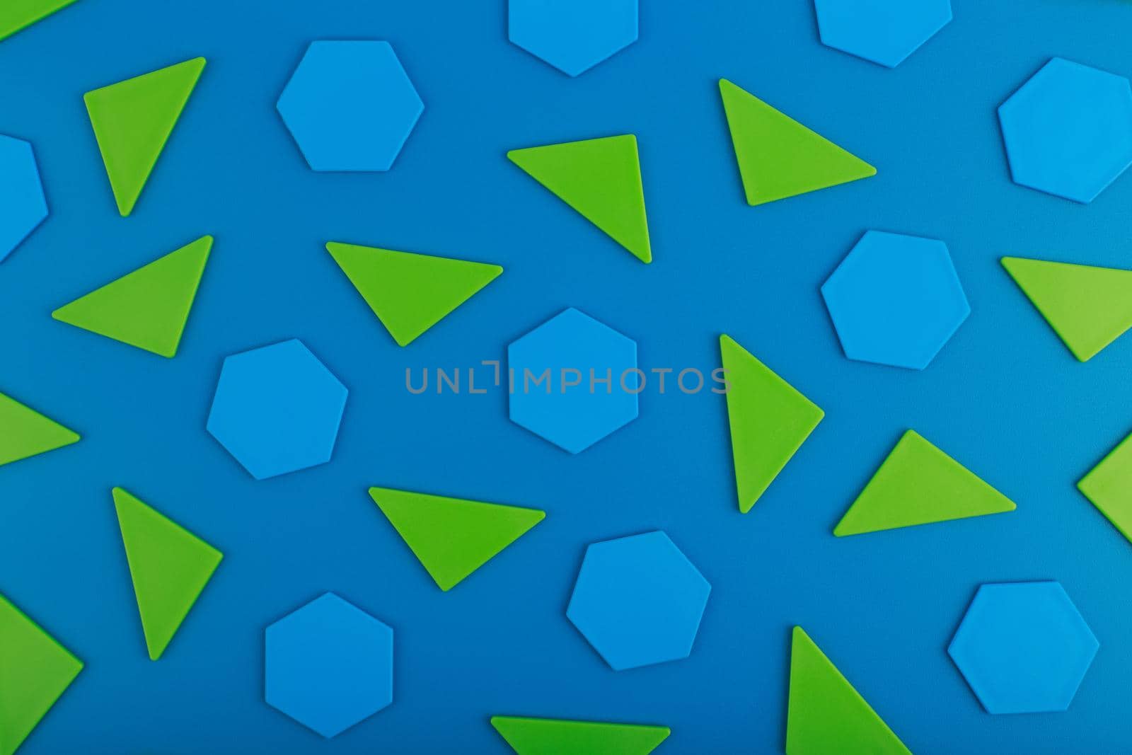 Flat lay with with green triangles and blue polygons on blue background. High quality photo
