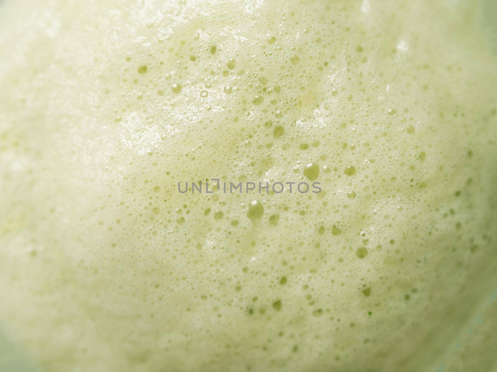 Green foam texture extreme close up as background. Perfect green matcha tea latte foam with bubbles macro shoot. Copy space for text.