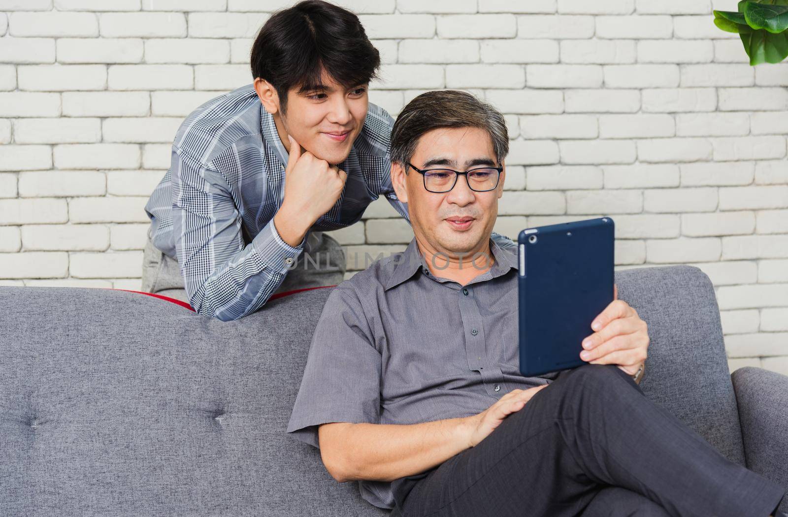 Father man and his son sit on sofa talking chatting on video call by Sorapop