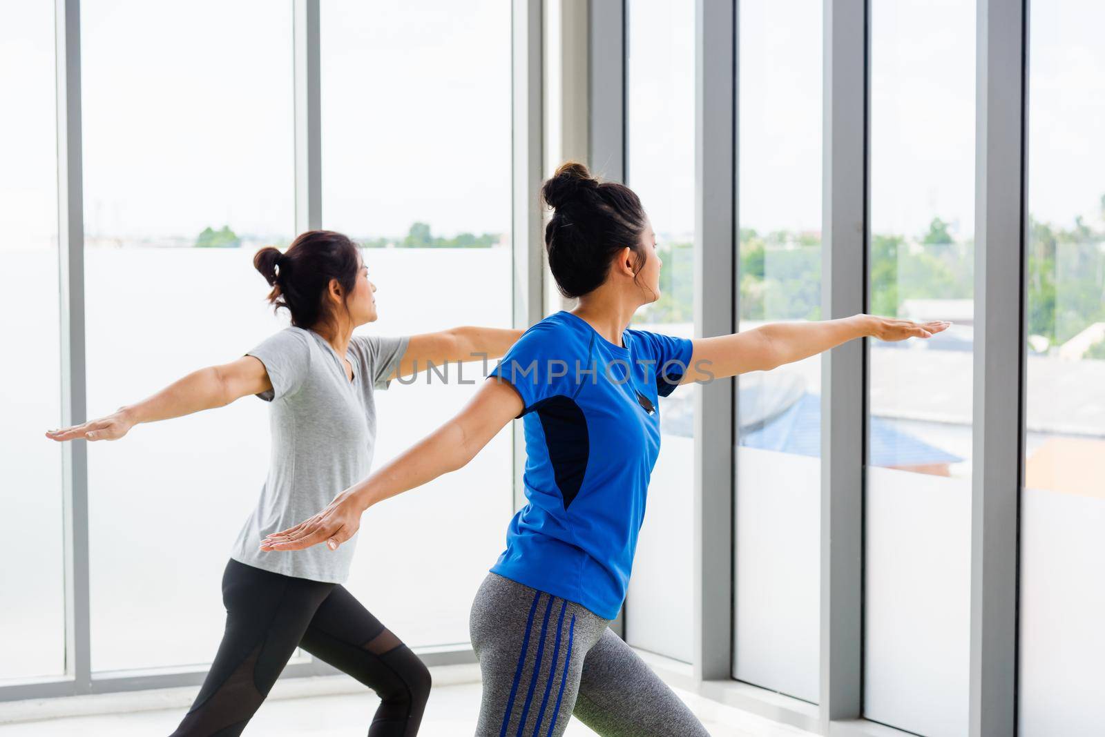 Two Asian women sporty attractive people practicing yoga lesson together by Sorapop
