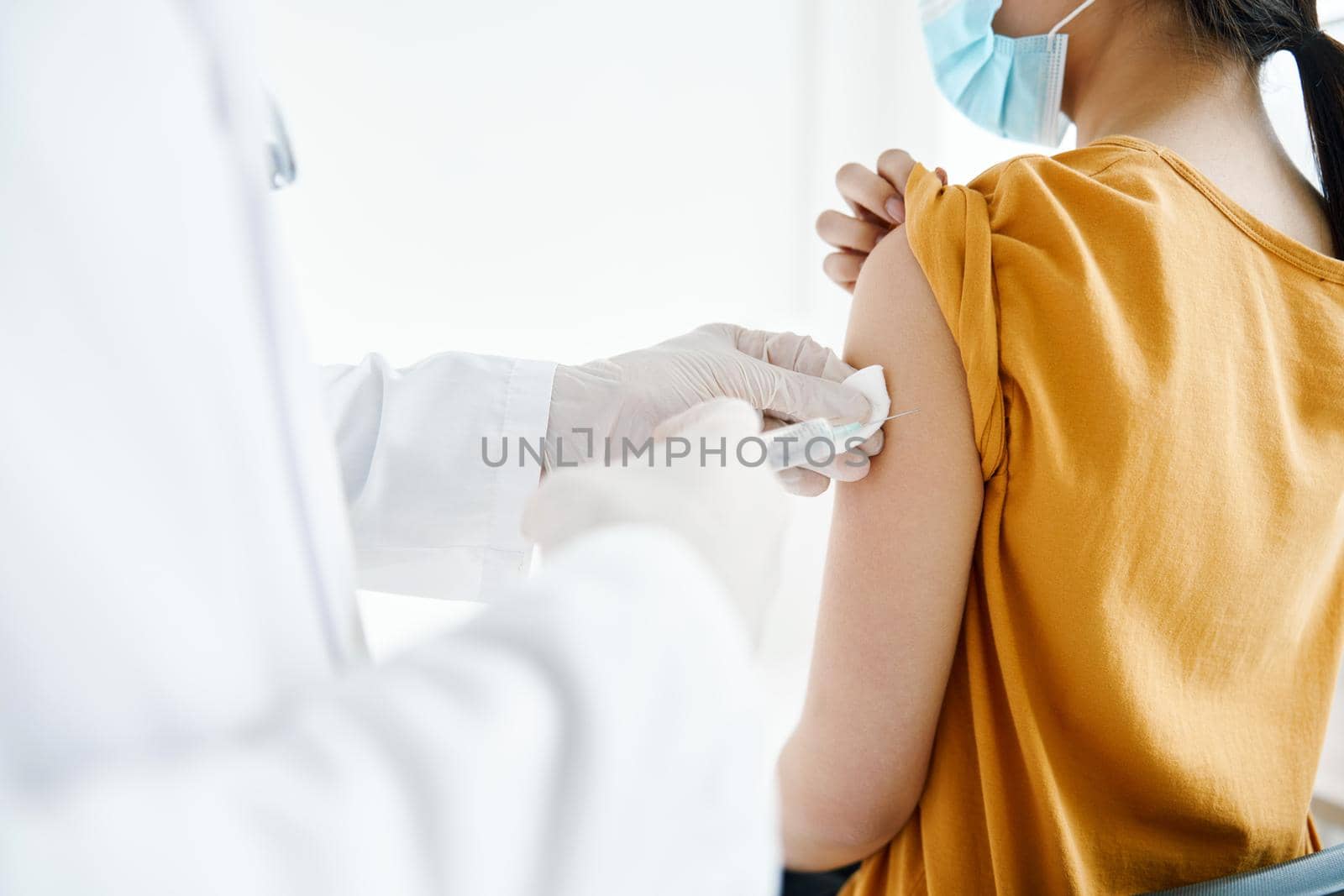doctor giving an injection to the patient's shoulder close-up cropped view covid vaccination by SHOTPRIME