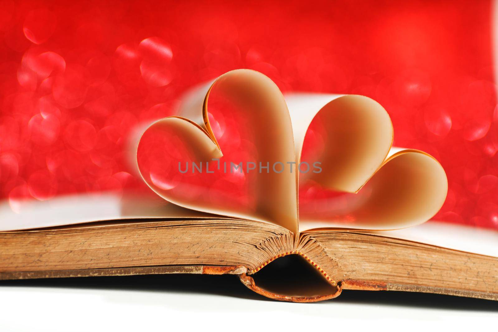 Pages of open book rolled in heart shape on glitter background, love reading, valentines day