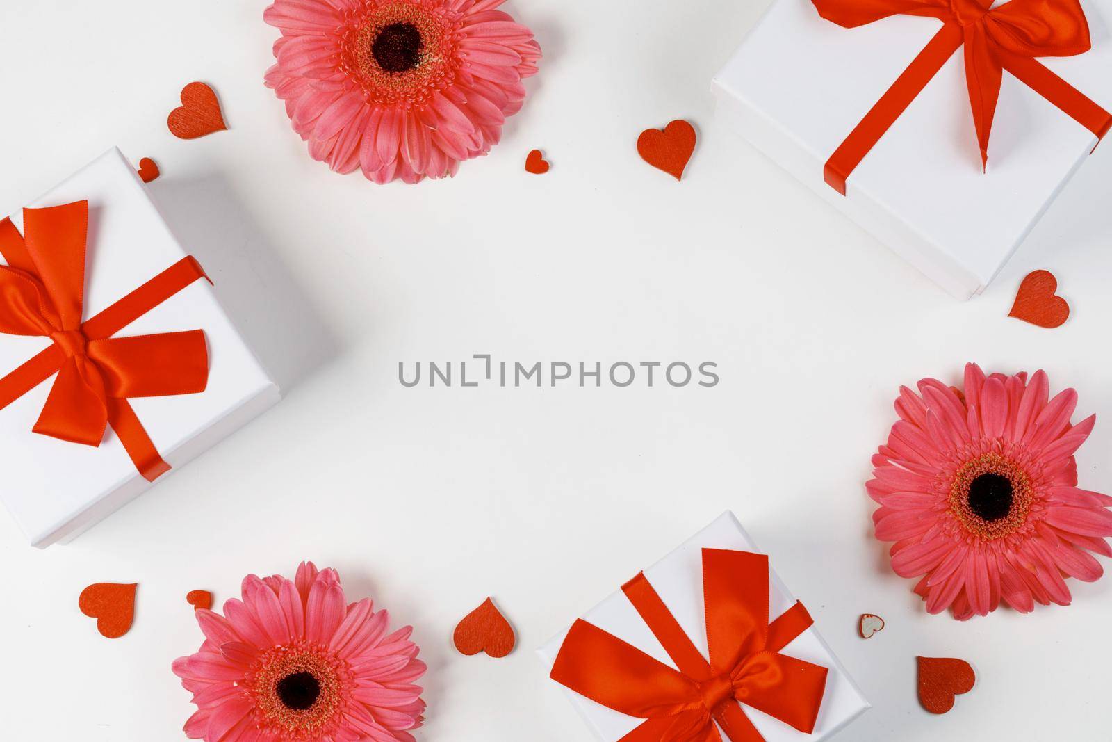 Pink gerbera flowers gifts and red hearts composition on white background top view with copy space. Valentine's day, birthday, wedding, Mother's day concept. Copy space